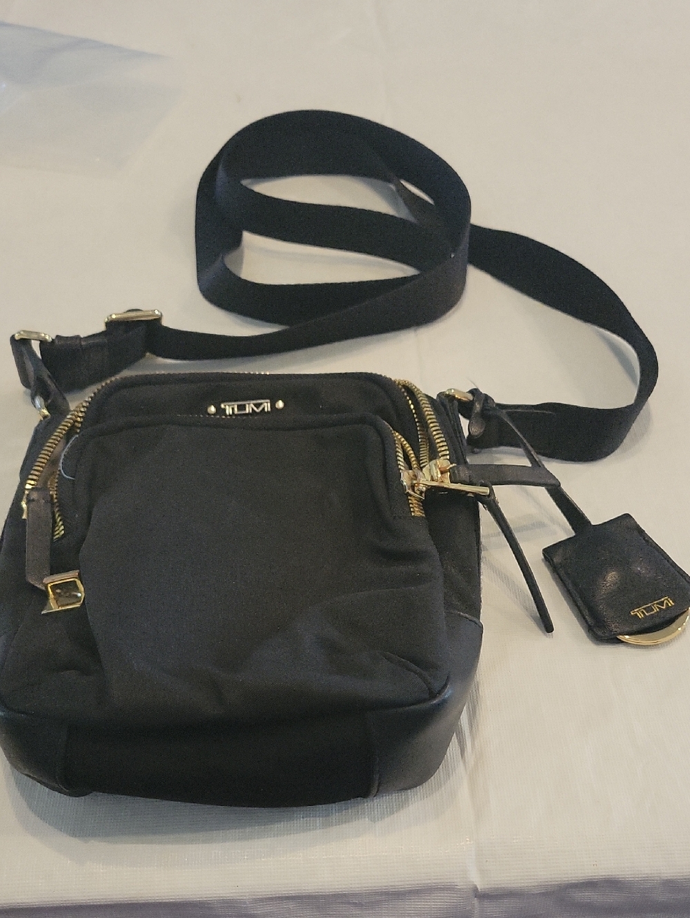 Tumi Black Crossbody Bag with Gold Hardware and Luggage Tag